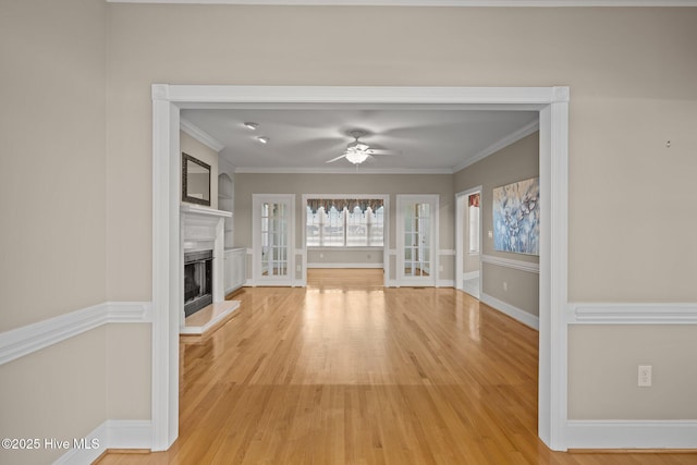 unfurnished living room with a fireplace with raised hearth, light wood finished floors, and crown molding