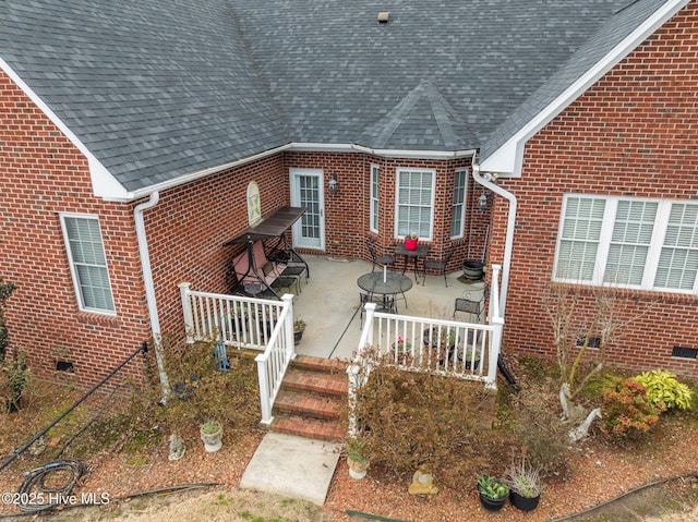 exterior space with crawl space, brick siding, a patio, and roof with shingles