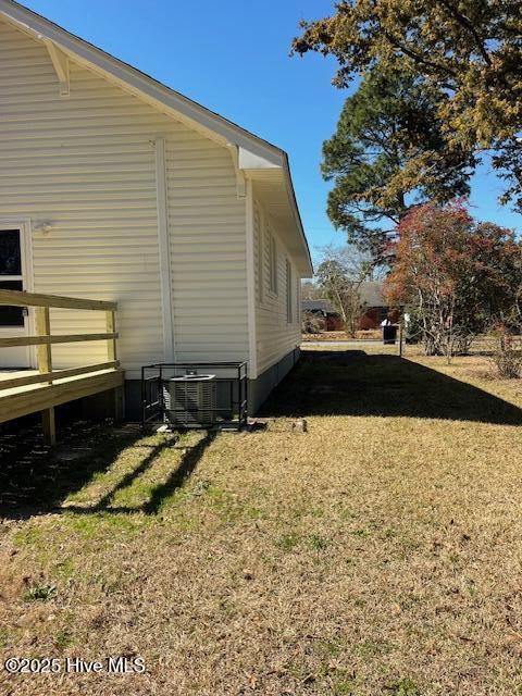 view of home's exterior with a yard, a wooden deck, and central AC unit