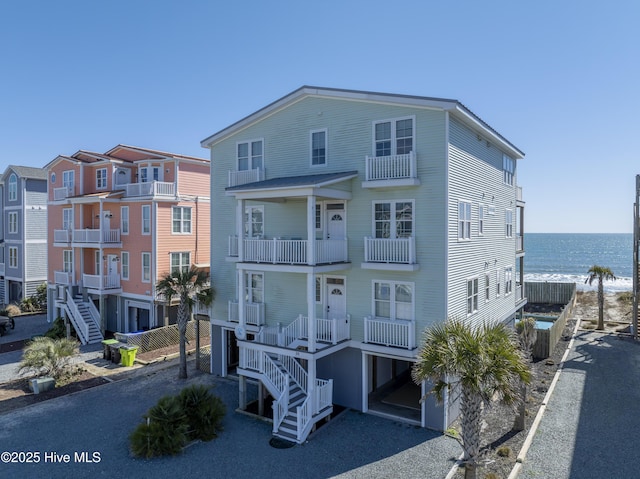 coastal home featuring driveway, a water view, and stairs