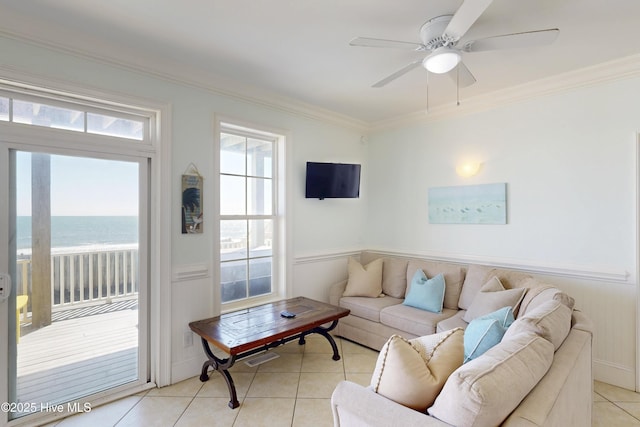 living area featuring a ceiling fan, a water view, crown molding, and light tile patterned flooring