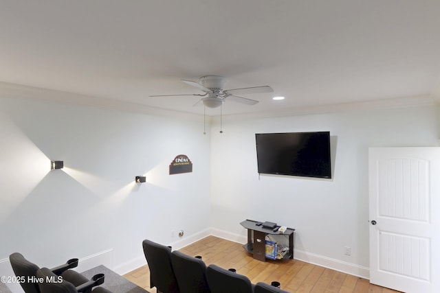 cinema room featuring ceiling fan, ornamental molding, light wood-type flooring, and baseboards