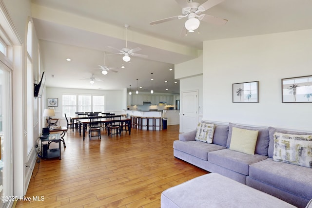 living room with high vaulted ceiling, recessed lighting, and light wood finished floors