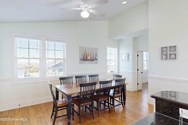 dining space featuring light wood-style floors, vaulted ceiling, baseboards, and ceiling fan