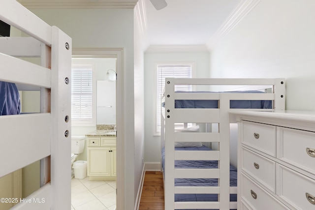 bedroom with baseboards, ornamental molding, and connected bathroom