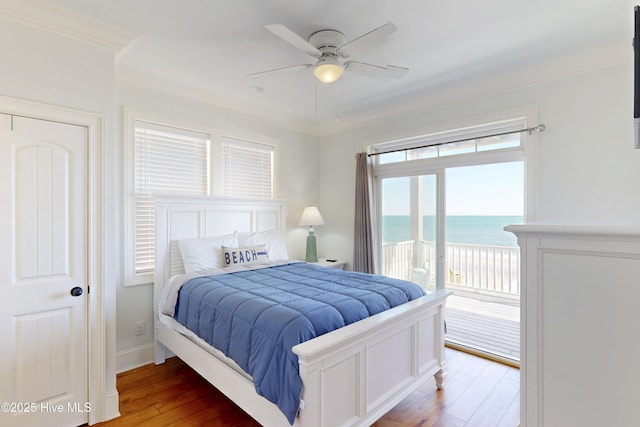 bedroom with crown molding, a water view, ceiling fan, wood finished floors, and access to outside