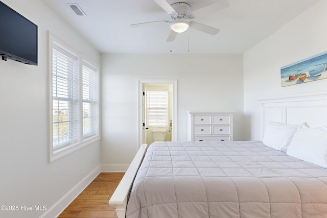 bedroom with connected bathroom, wood finished floors, a ceiling fan, visible vents, and baseboards