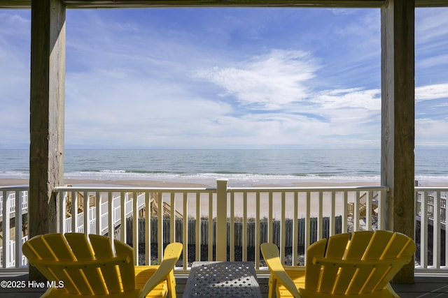 balcony with a water view and a view of the beach