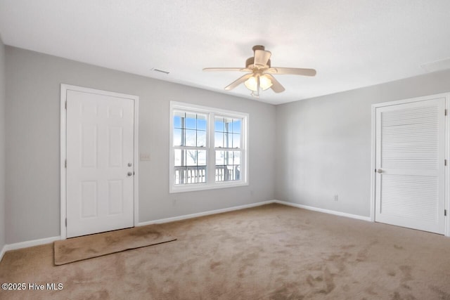 carpeted entryway with ceiling fan and baseboards