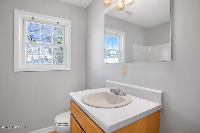 half bathroom with visible vents, toilet, vanity, and baseboards