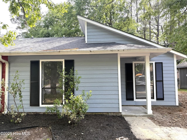view of side of home with roof with shingles