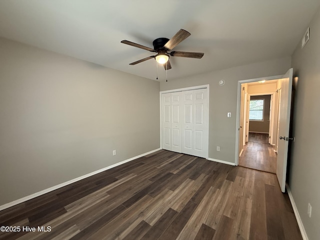 unfurnished bedroom with visible vents, ceiling fan, baseboards, a closet, and dark wood-style flooring