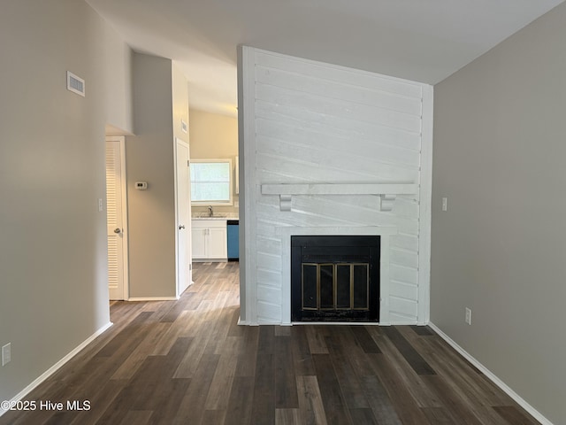 unfurnished living room featuring dark wood-style floors, visible vents, a fireplace, and baseboards