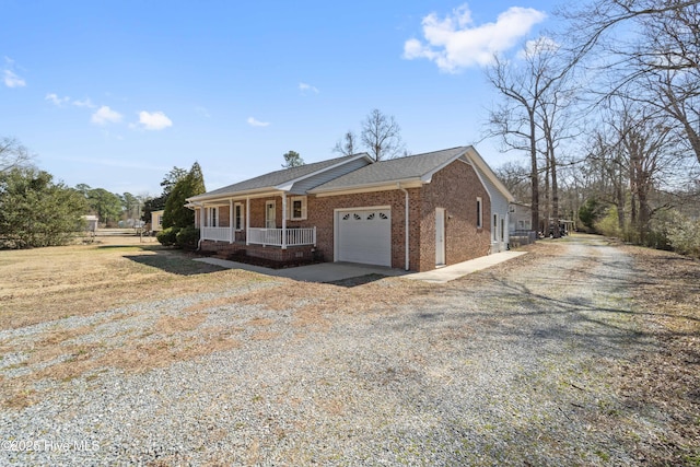 view of front of property featuring brick siding, roof with shingles, covered porch, a garage, and driveway