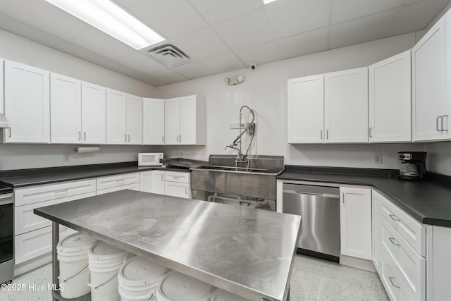 kitchen featuring white cabinets, visible vents, stainless steel appliances, and light speckled floor