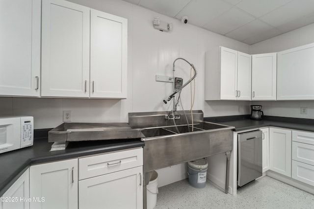 kitchen with dark countertops, white microwave, white cabinets, and dishwasher