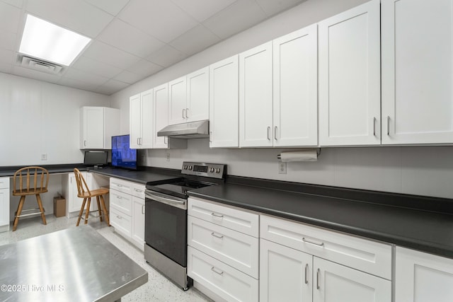 kitchen featuring under cabinet range hood, visible vents, built in study area, stainless steel electric range oven, and dark countertops