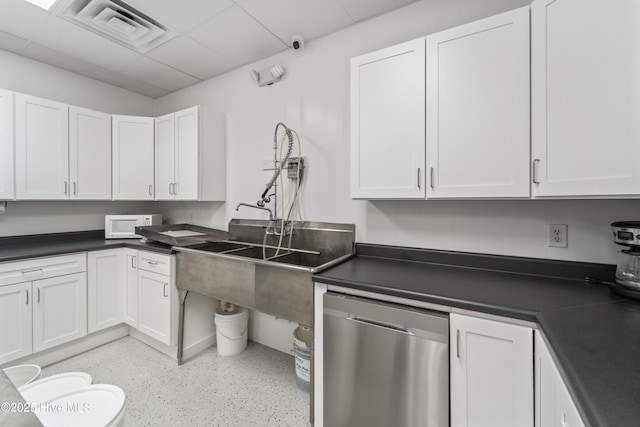 kitchen with dishwasher, white microwave, dark countertops, and visible vents