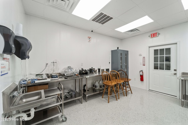 kitchen featuring visible vents, a drop ceiling, and speckled floor