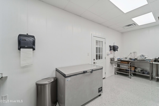 miscellaneous room with a drop ceiling, visible vents, and speckled floor