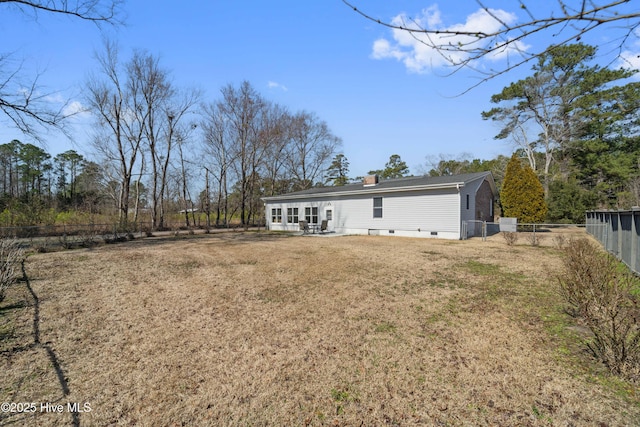 rear view of house featuring a yard, a patio, a chimney, and fence