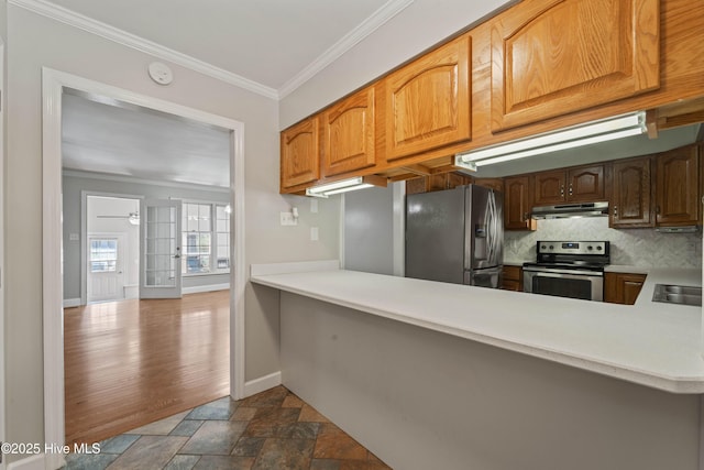 kitchen with stainless steel appliances, ornamental molding, stone finish floor, under cabinet range hood, and baseboards