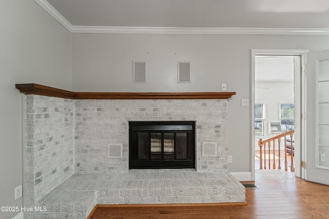 interior details with visible vents, crown molding, a fireplace, and wood finished floors