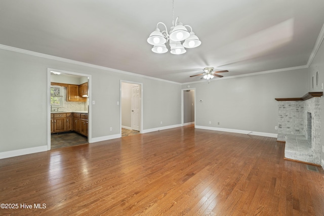 unfurnished living room with a brick fireplace, dark wood-style flooring, crown molding, and baseboards