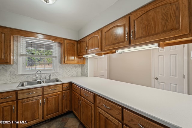 kitchen with brown cabinets, light countertops, visible vents, decorative backsplash, and a sink