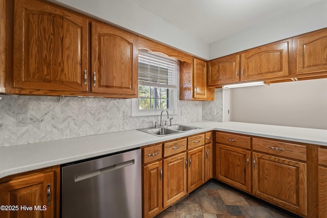 kitchen with a sink, light countertops, dishwasher, stone finish flooring, and brown cabinetry