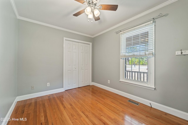 unfurnished bedroom featuring baseboards, crown molding, and wood finished floors