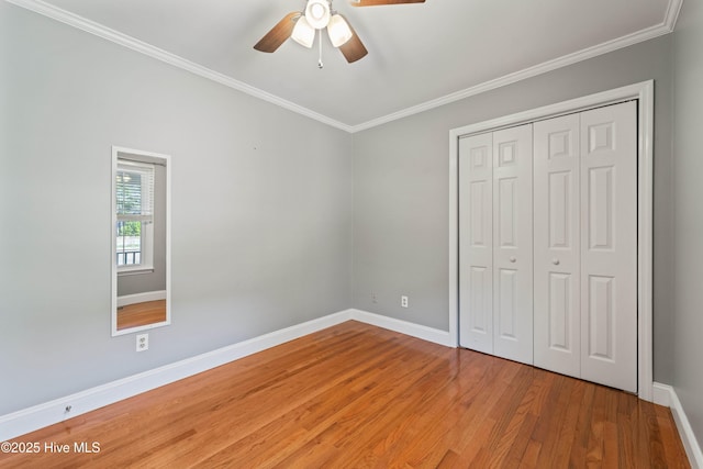 unfurnished bedroom featuring crown molding, a closet, ceiling fan, light wood-type flooring, and baseboards