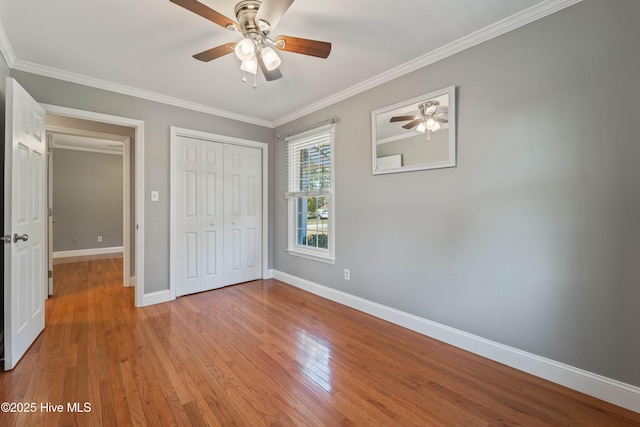 unfurnished bedroom featuring baseboards, ceiling fan, crown molding, light wood-type flooring, and a closet