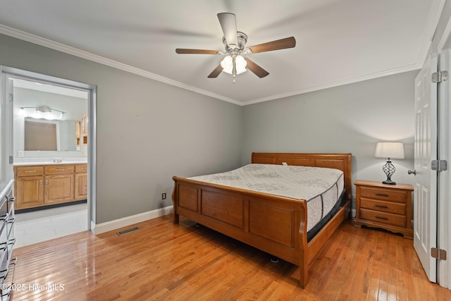 bedroom featuring crown molding, light wood finished floors, visible vents, ensuite bathroom, and baseboards