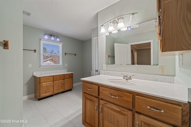 bathroom featuring baseboards, visible vents, a textured ceiling, and vanity