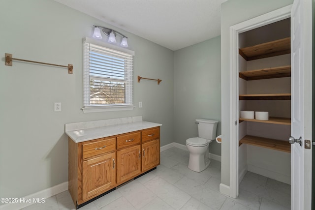 bathroom featuring marble finish floor, toilet, vanity, and baseboards