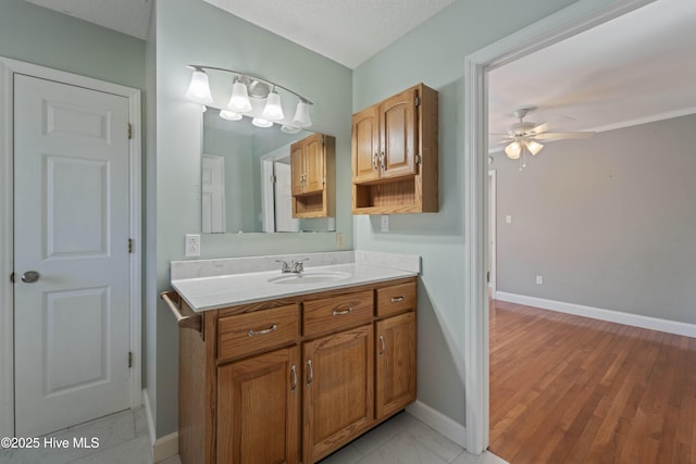 bathroom with a textured ceiling, vanity, a ceiling fan, and baseboards