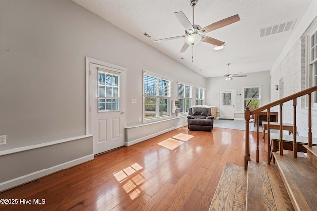 sitting room with a textured ceiling, hardwood / wood-style flooring, visible vents, and baseboards