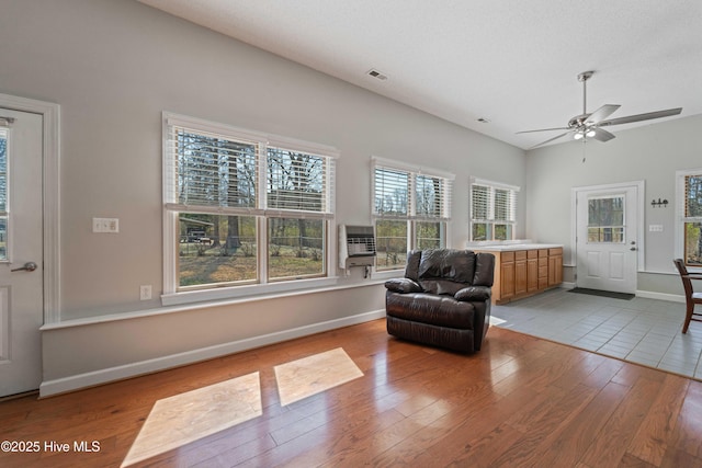 sitting room with wood finished floors, a ceiling fan, visible vents, baseboards, and heating unit