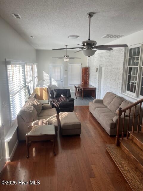 living area featuring ceiling fan, a textured ceiling, visible vents, and wood finished floors