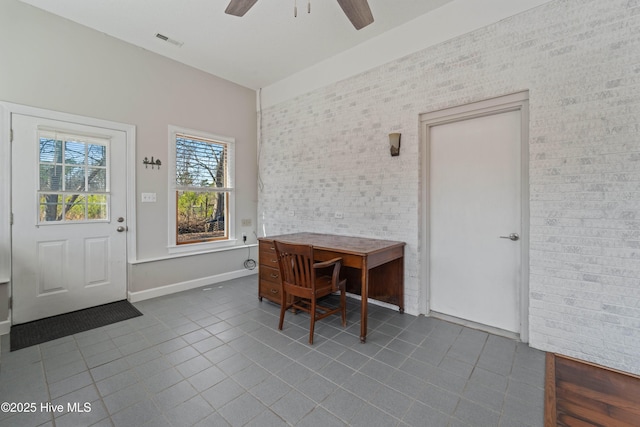 tiled home office featuring baseboards, brick wall, visible vents, and a ceiling fan