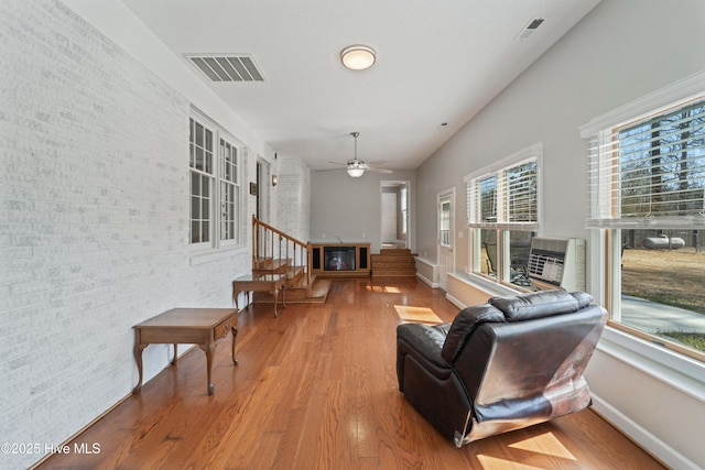 living area with wood finished floors, a glass covered fireplace, visible vents, and baseboards