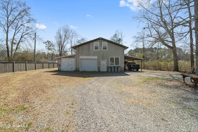 exterior space featuring driveway, fence, and an outbuilding