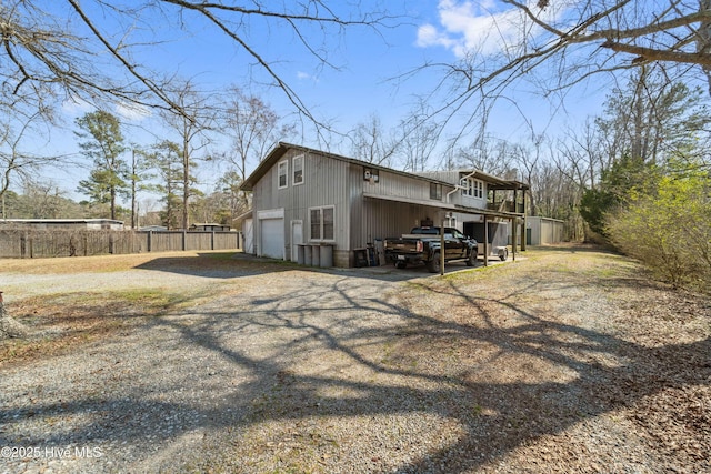 back of house featuring a garage, gravel driveway, and fence