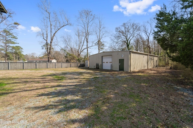 view of yard with a garage, fence, and an outbuilding