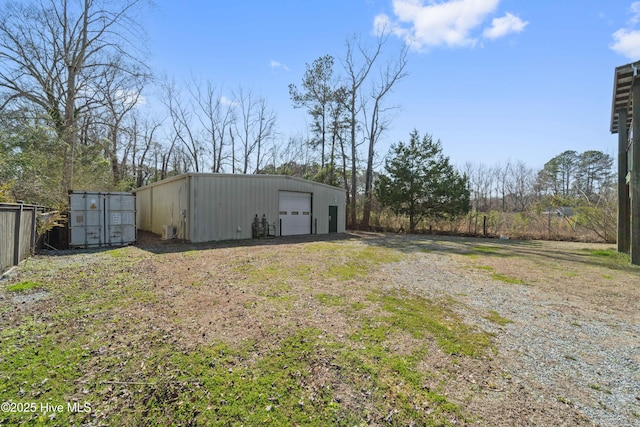 view of yard with dirt driveway, a detached garage, and an outbuilding