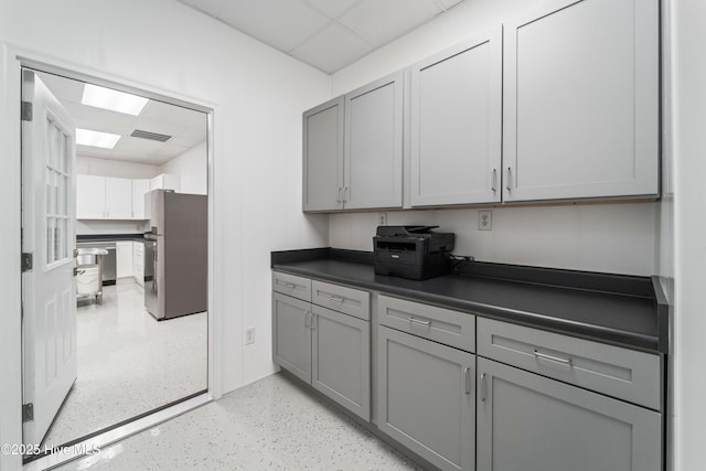 kitchen featuring a drop ceiling, dark countertops, gray cabinets, and freestanding refrigerator