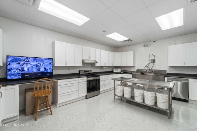 kitchen featuring appliances with stainless steel finishes, dark countertops, white cabinets, and under cabinet range hood