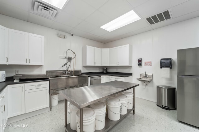 kitchen featuring appliances with stainless steel finishes, a drop ceiling, visible vents, and white cabinetry