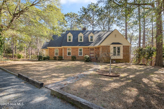 cape cod home with a chimney and brick siding